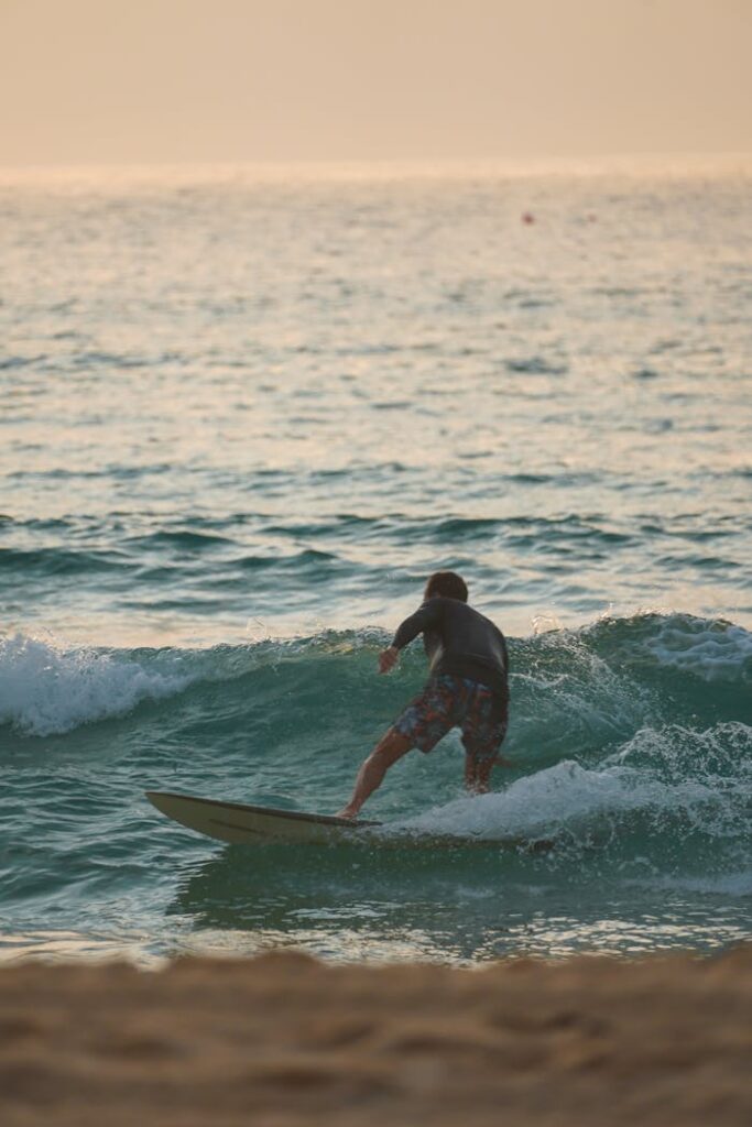 A surfer skillfully rides a wave during sunset, showcasing the thrill of ocean adventure.