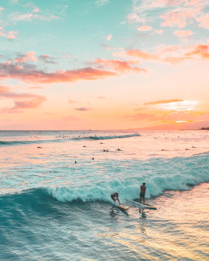 Vibrant sunset beach scene with surfers catching waves, ideal for travel and leisure themes.